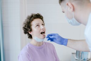 Doctor performing an oral and throat examination on a patient in a clinic, illustrating when to see a professional about tonsil stones