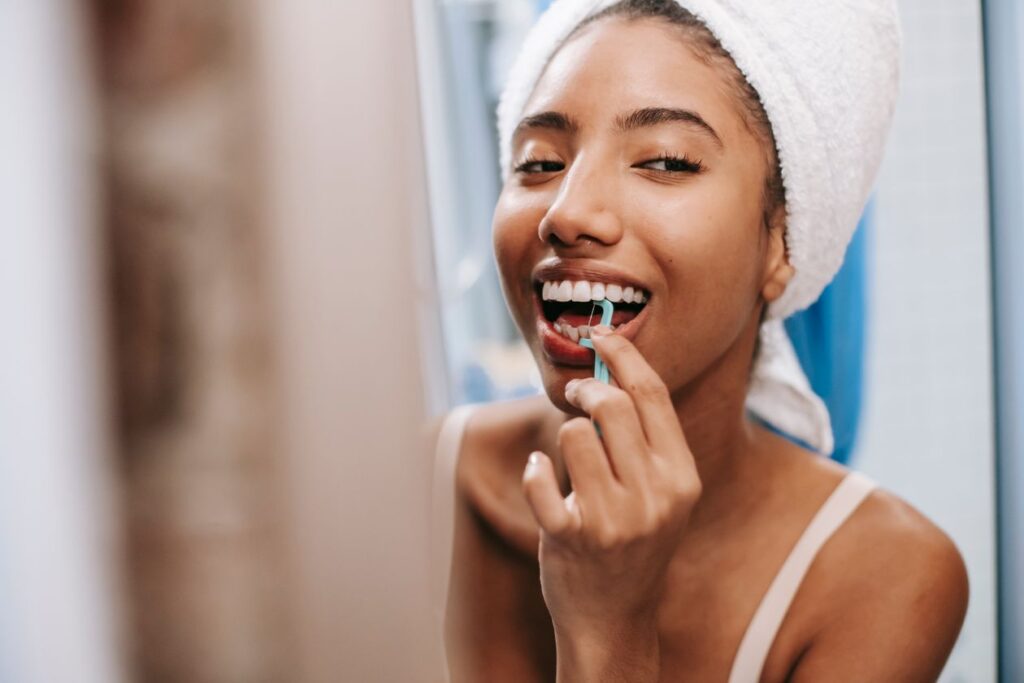 Cheerful woman flossing her teeth as part of her daily oral care routine