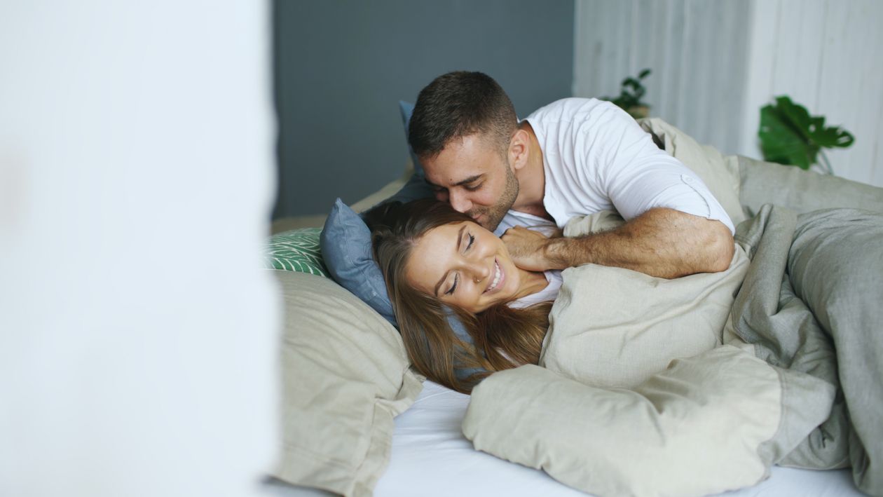 Why Your Partner Is Pulling Away (And What Bad Breath Has to Do With It) 1 Couple embracing in bed with soft lighting, intimate closeness and connection restored
