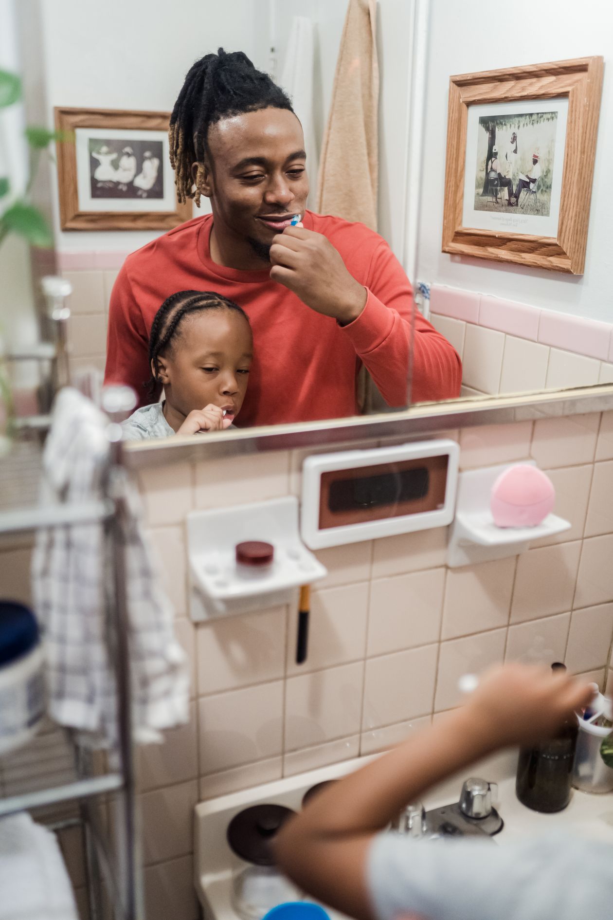 Father and daughter brushing their teeth together in the bathroom as part of a daily oral care routine