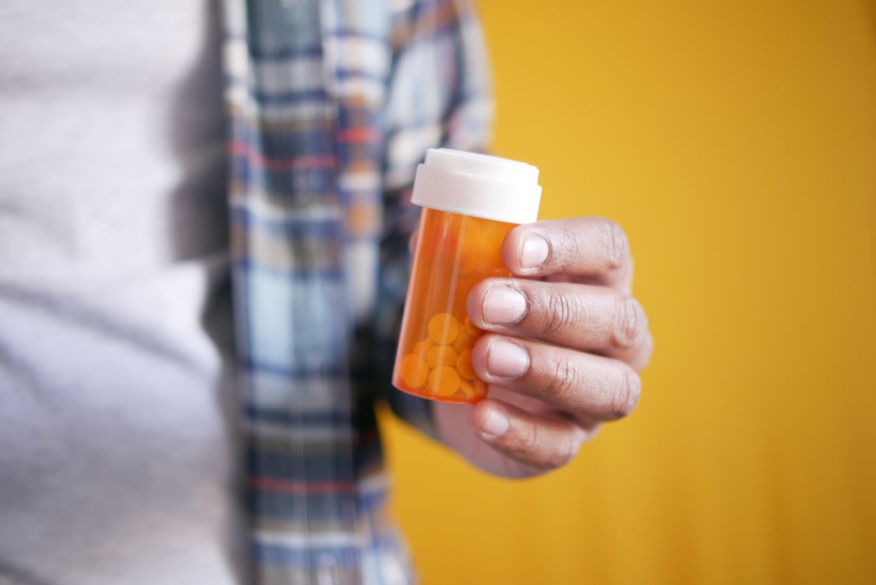 Oral Probiotics After Antibiotics 1 Hand holding a box of pills, representing a course of antibiotics that can disrupt the oral microbiome