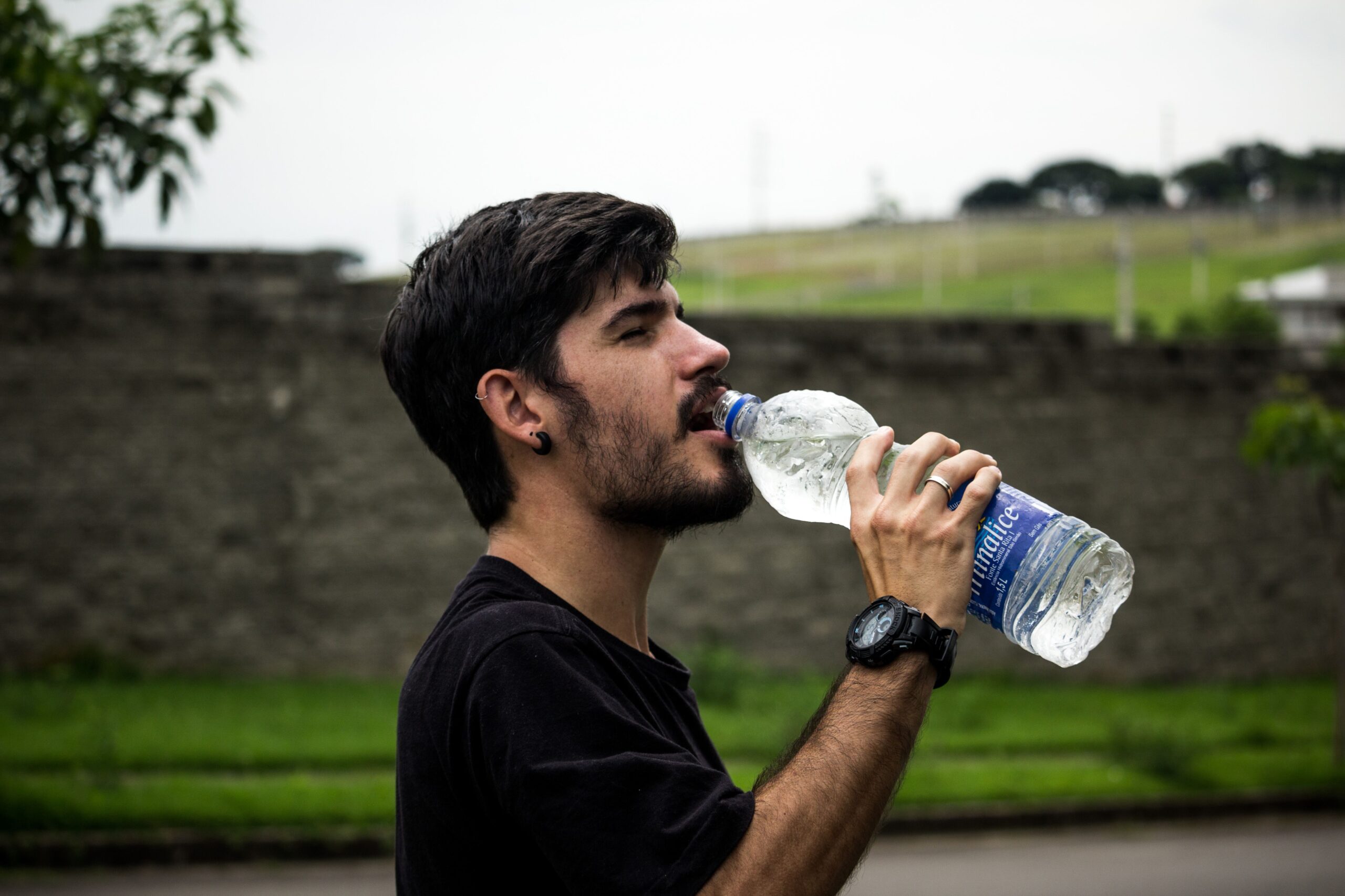 Man in black shirt drinking water to support oral hydration and salivary gland function