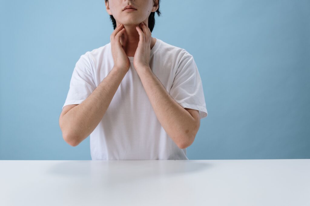 Man holding his neck, reflecting the throat discomfort caused by tonsil stones and bacterial imbalance