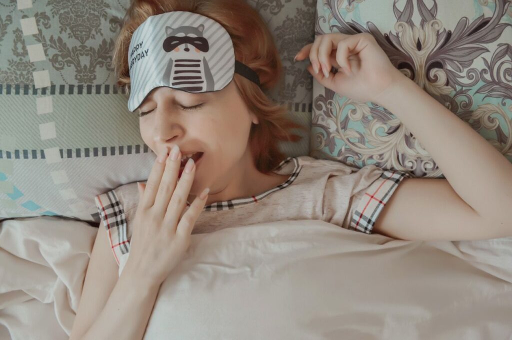 Sleepy woman yawning on her bed in the morning, when morning breath is at its worst