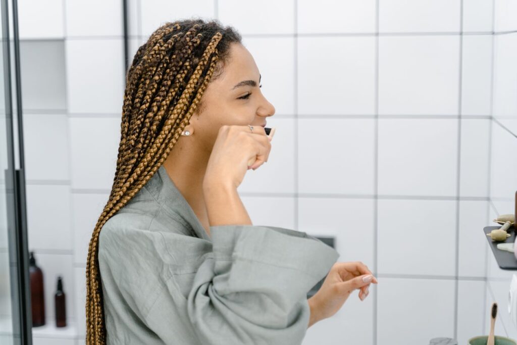 Woman brushing her teeth to help remove plaque and keep her mouth healthy