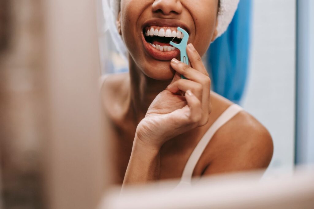 Reflection of a woman cleaning her teeth in the mirror, part of a daily routine to support gum health
