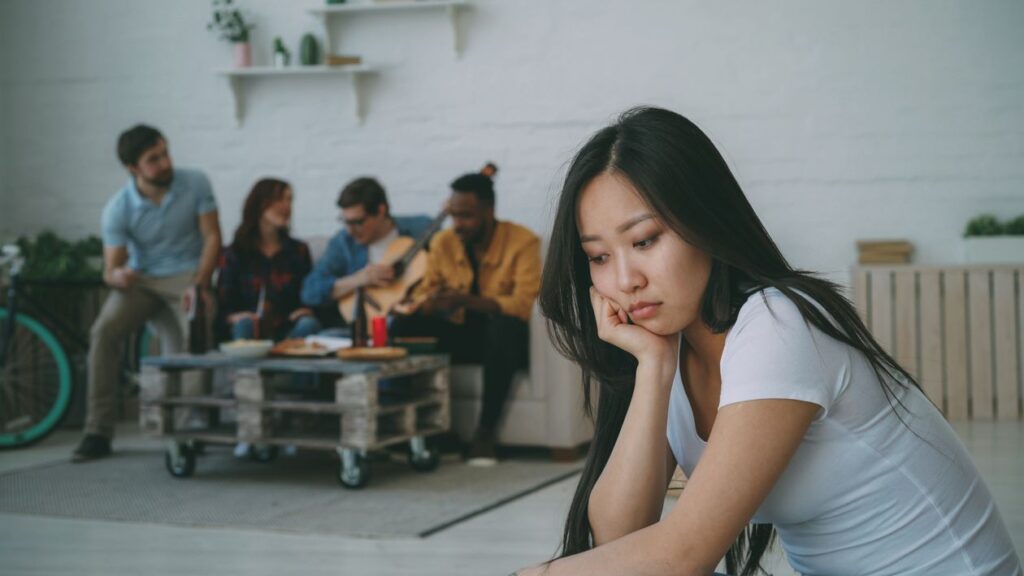 Young woman feeling left out at a social gathering, isolated and withdrawn from group connection
