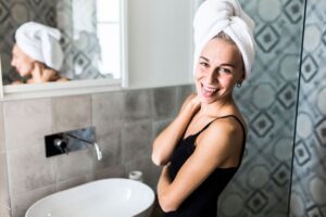 Woman with a towel wrapped on her head during her daily oral care and skincare routine