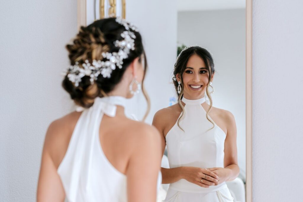 Bride smiling at her reflection in a mirror while getting ready, worried about bad breath before her wedding day