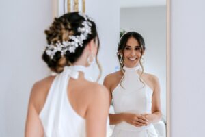 Bride smiling at her reflection in a mirror while getting ready, worried about bad breath before her wedding day