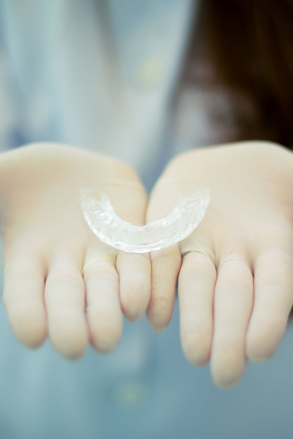 Bad Breath From Braces, Aligners and Retainers: The Real Cause 1 Clear retainer held in gloved hands, showing the smooth surface where bacteria build up and cause bad breath