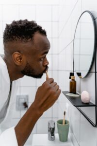 Man brushing his teeth at the bathroom mirror as part of a daily routine to stop bad breath