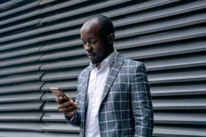 Man in a plaid coat checking his smartphone, waiting for a text after a first date that never turns into a second date