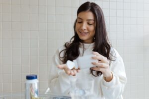Woman reading a supplement bottle label, checking whether the probiotic strains are right for oral health
