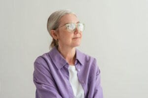 Composed grey-haired woman in eyeglasses, managing bad breath during perimenopause and menopause