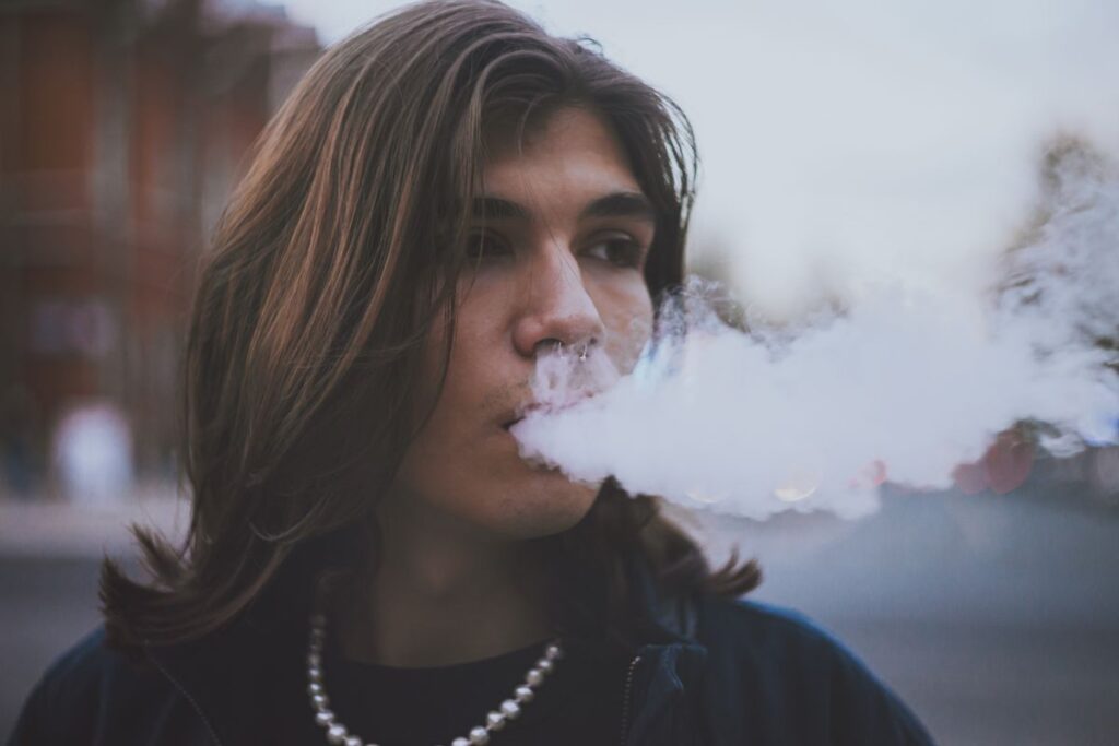 Person exhaling vapor outdoors, illustrating bad breath from vaping