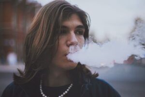 Person exhaling vapor outdoors, illustrating bad breath from vaping
