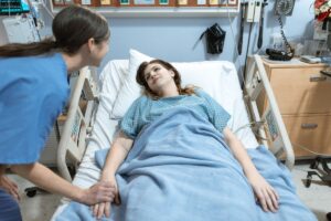 Nurse in a close-contact job leaning over a patient's bedside during a long shift