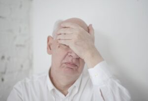 Man sitting with his hand over his face after someone told him he has bad breath