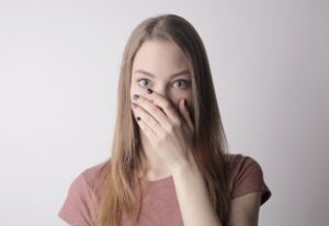 Woman covering her mouth with her hand, unsure what her bad breath smell might mean
