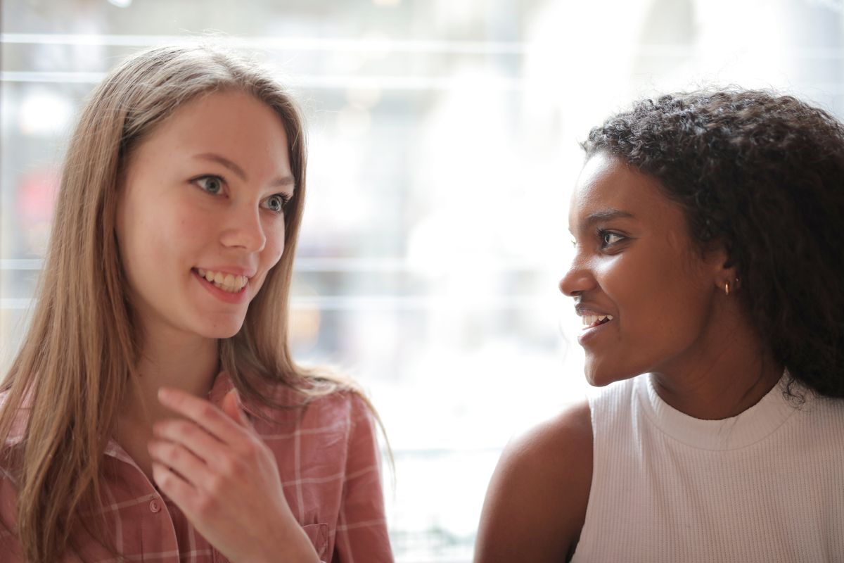 Why Garlic Breath Won't Go Away — And What Finally Does 2 Two women smiling and talking closely, at ease with fresh breath in conversation
