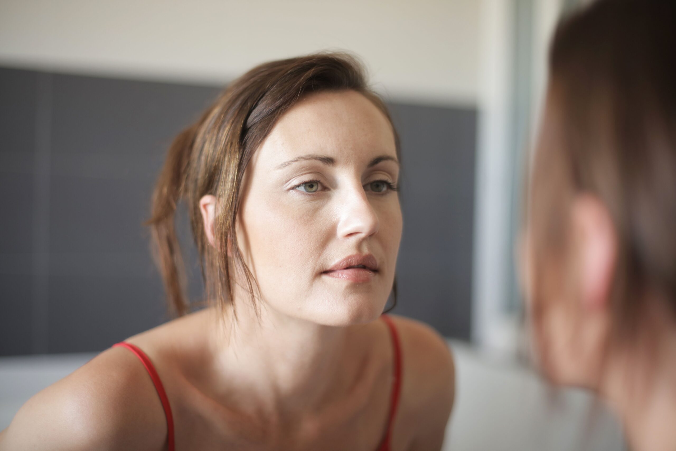 Woman checking her breath in the bathroom mirror weeks after a dental cleaning