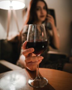 Woman holding a glass of red wine in warm light, before bad breath after drinking alcohol sets in