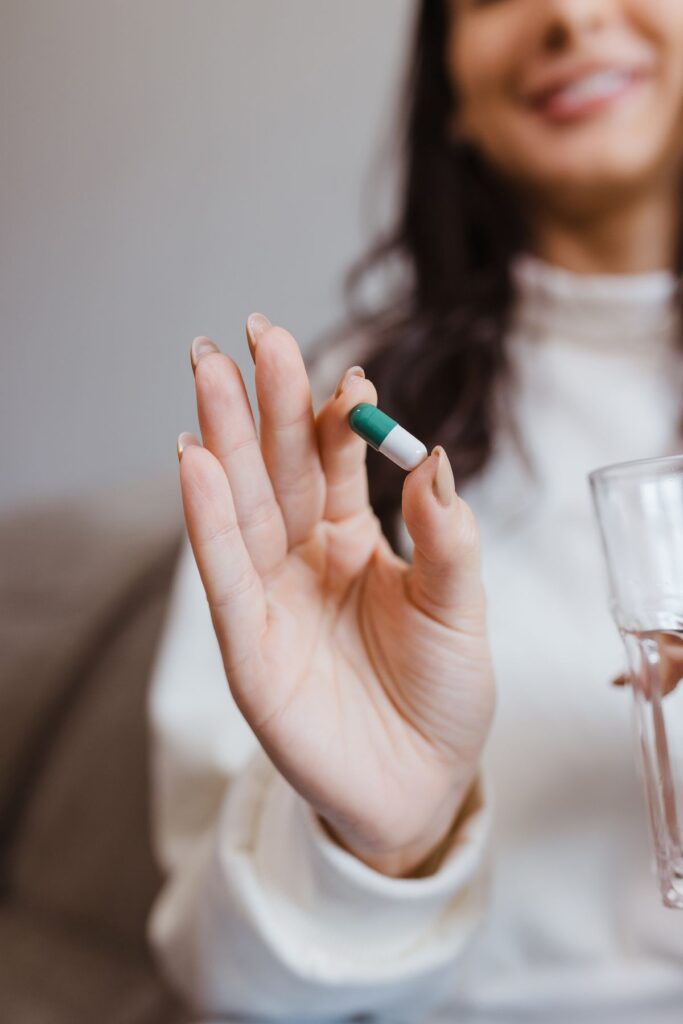 Woman holding a capsule and a glass of water, wondering why her oral probiotic is not working