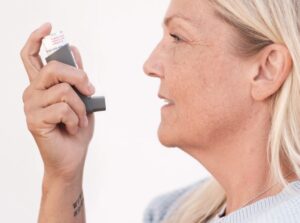 Woman using an asthma inhaler, a common trigger for oral thrush that keeps coming back