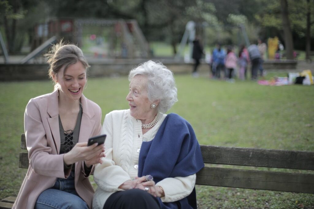 Adult daughter sitting with her elderly mother on a bench, wondering what to do about her parent's bad breath