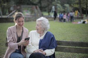 Adult daughter sitting with her elderly mother on a bench, wondering what to do about her parent's bad breath