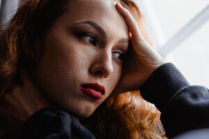 Pensive woman by a window, thinking about having had bad breath for years