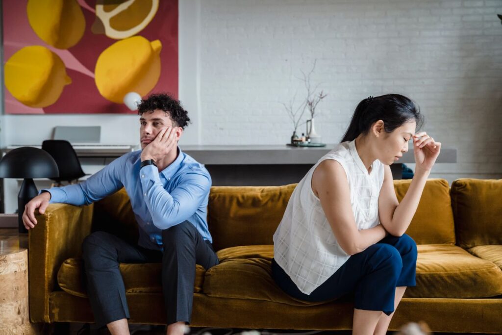 Couple sitting apart and unhappy on a sofa because my partner has bad breath and nothing changed