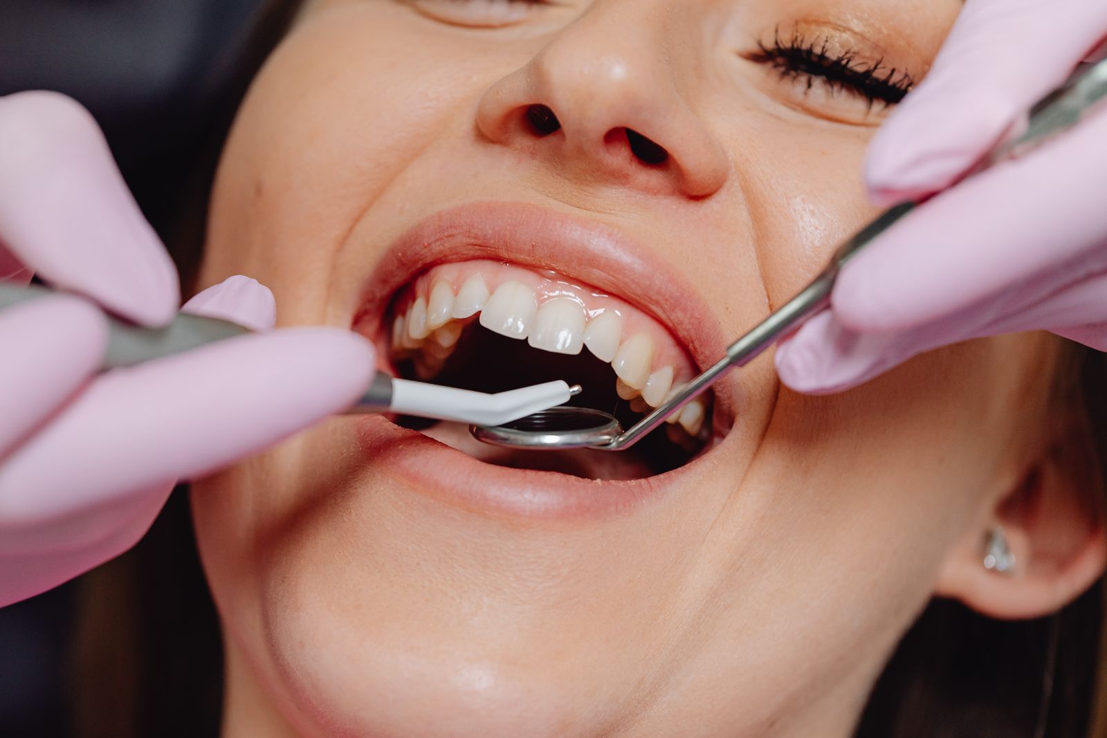 Smiling woman at a dental checkup, keeping her own teeth despite a family history of gum disease