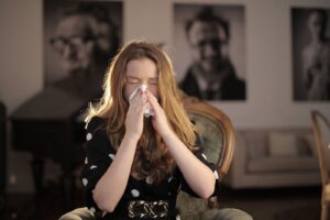 Woman wiping her nose with a tissue while recovering from a cold, a common trigger for bad breath after being sick