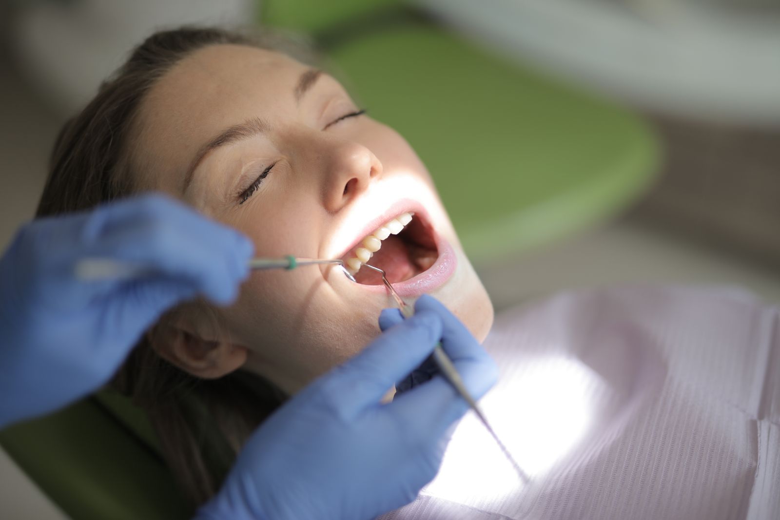 Dentist checking a woman's gums during an exam for early signs of inherited gum disease