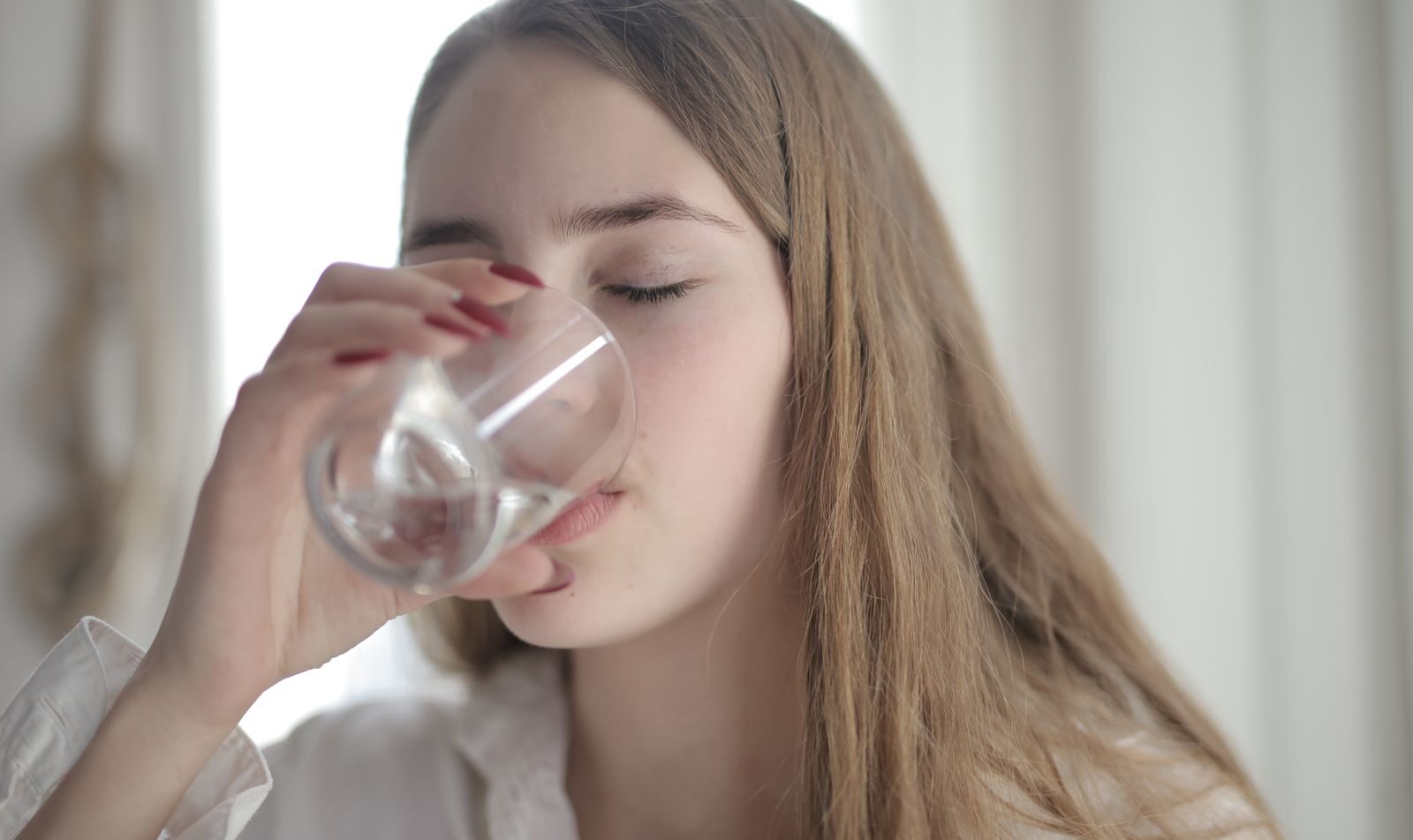 Woman drinking a glass of water to ease dry mouth and bad breath while taking a GLP-1 medication