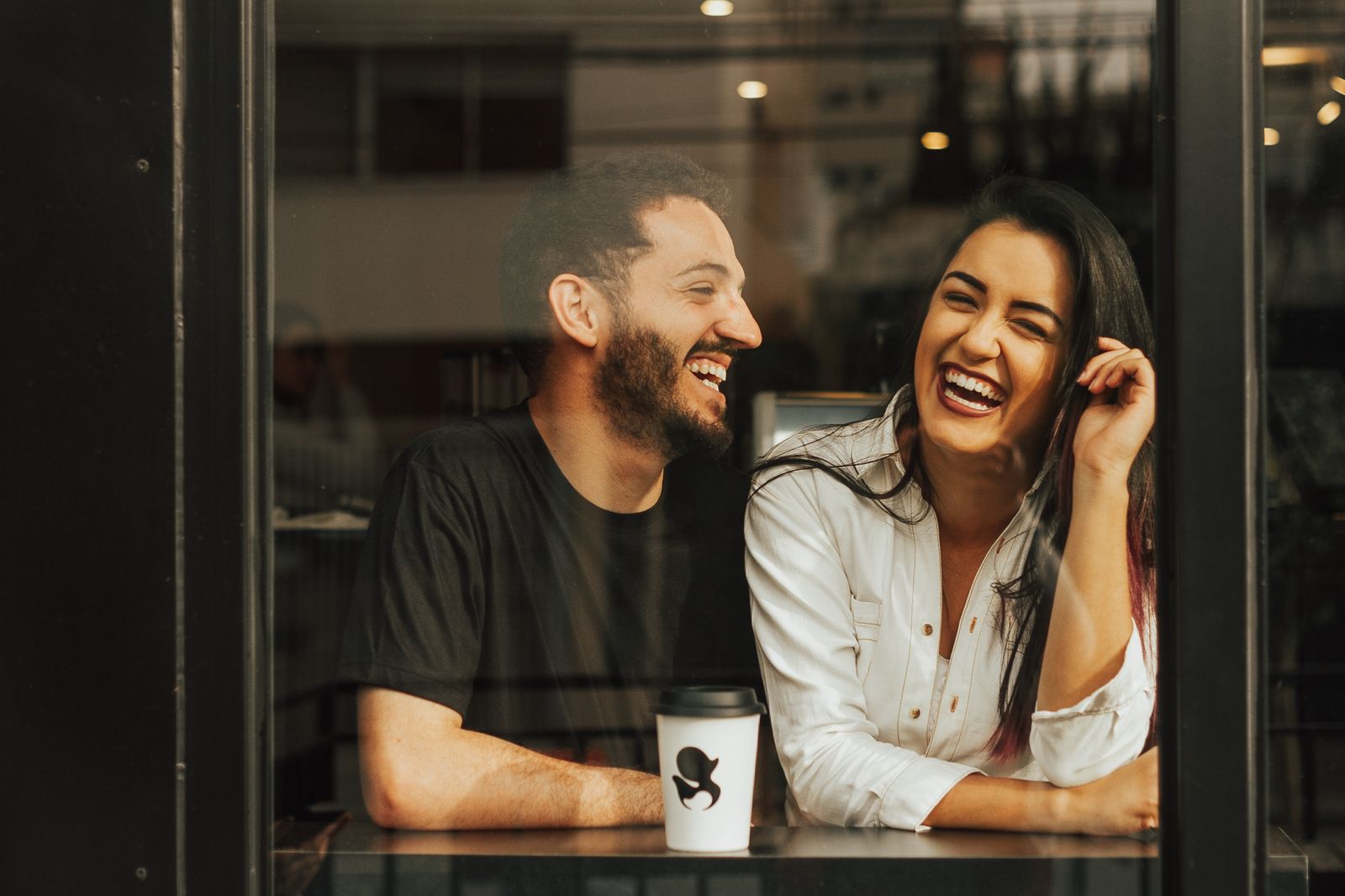 Couple laughing together in a cafe on a date, relaxed about the first kiss after divorce