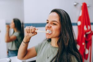 Woman brushing her teeth as part of a routine to keep breath fresh all month
