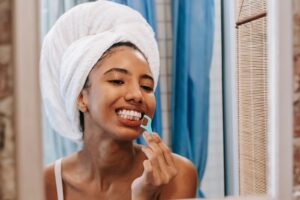Woman flossing in the mirror as part of a daily routine to stop her floss from smelling