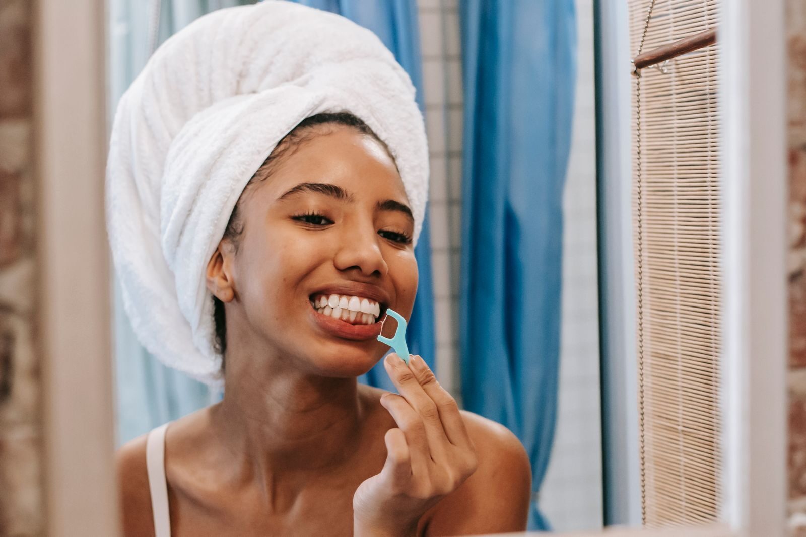 Why Does My Floss Smell Bad? What It Means and How to Stop It 3 Woman flossing in the mirror as part of a daily routine to stop her floss from smelling