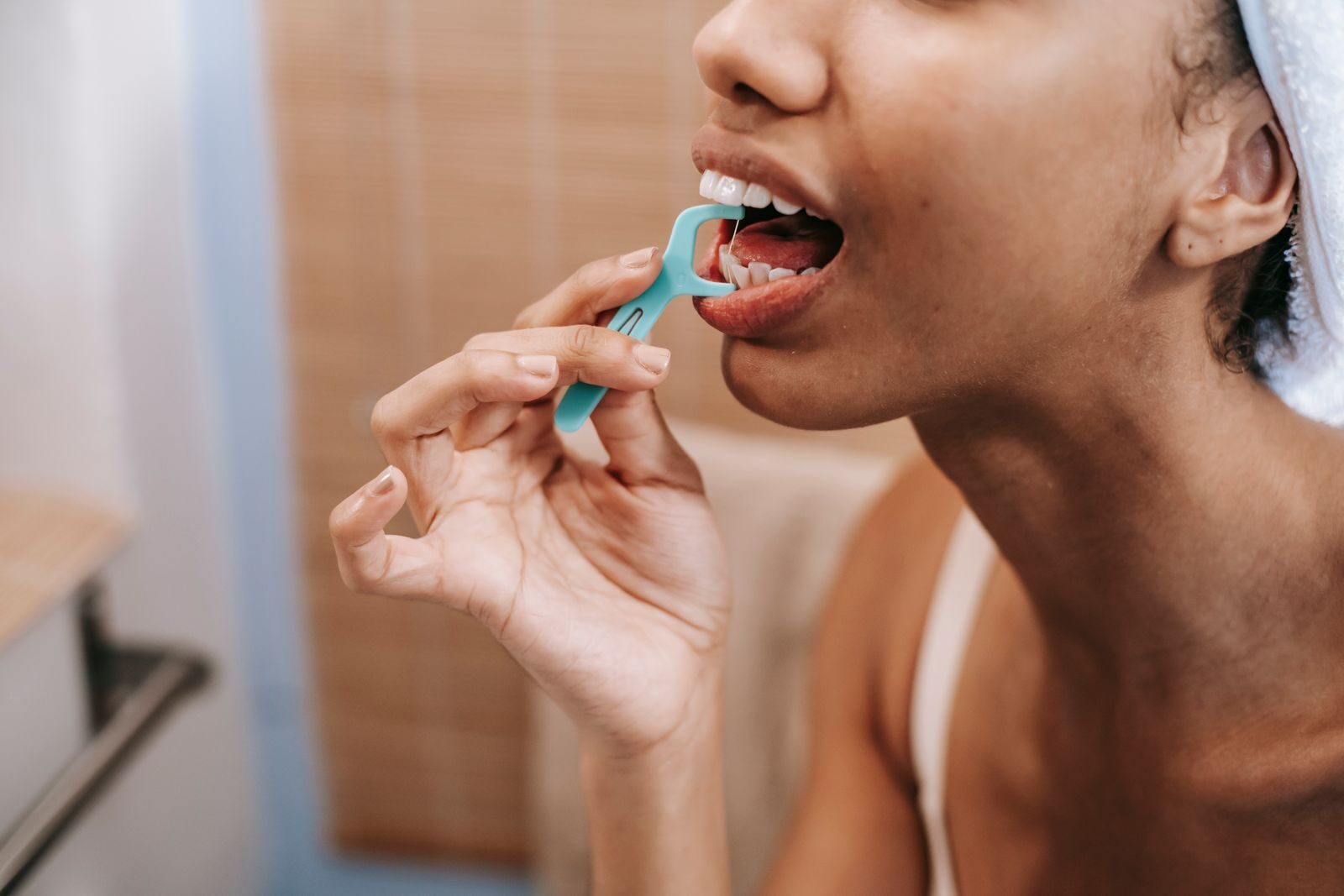 Why Does My Floss Smell Bad? What It Means and How to Stop It 1 Woman flossing her teeth at home and wondering why her floss smells bad afterward
